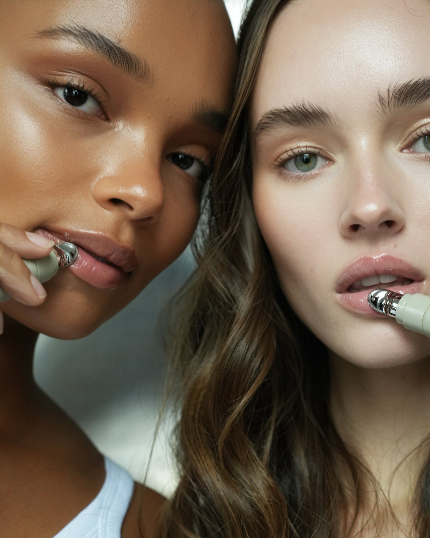 Two women with close-up views of their faces, wearing white tops.