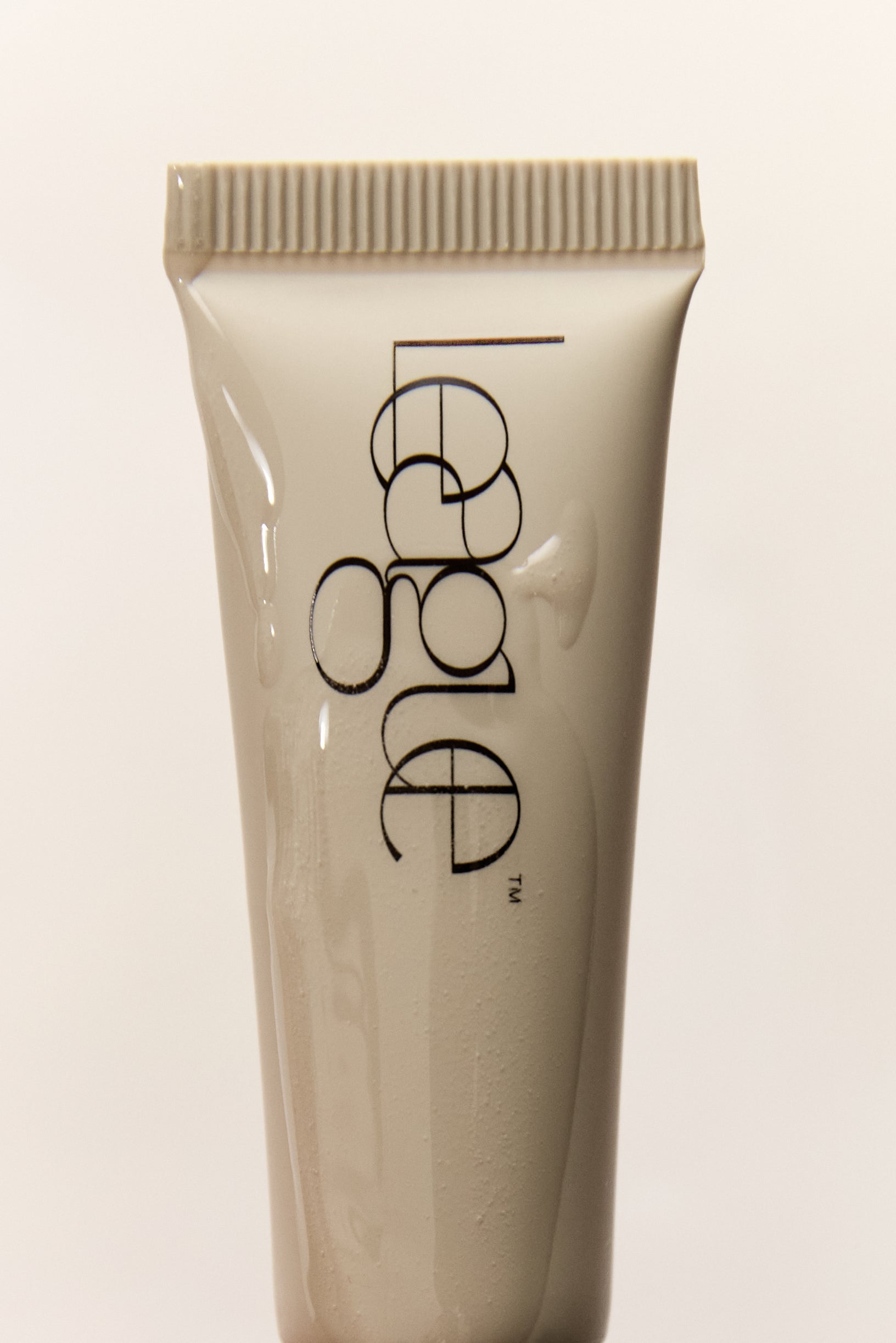 Tube of cosmetic cream with a brand logo on a light background